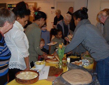 Mennesker af forskellige etniciteter tager mad fra fælles buffet.